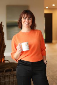 a woman smiling and confidently holding a white mug