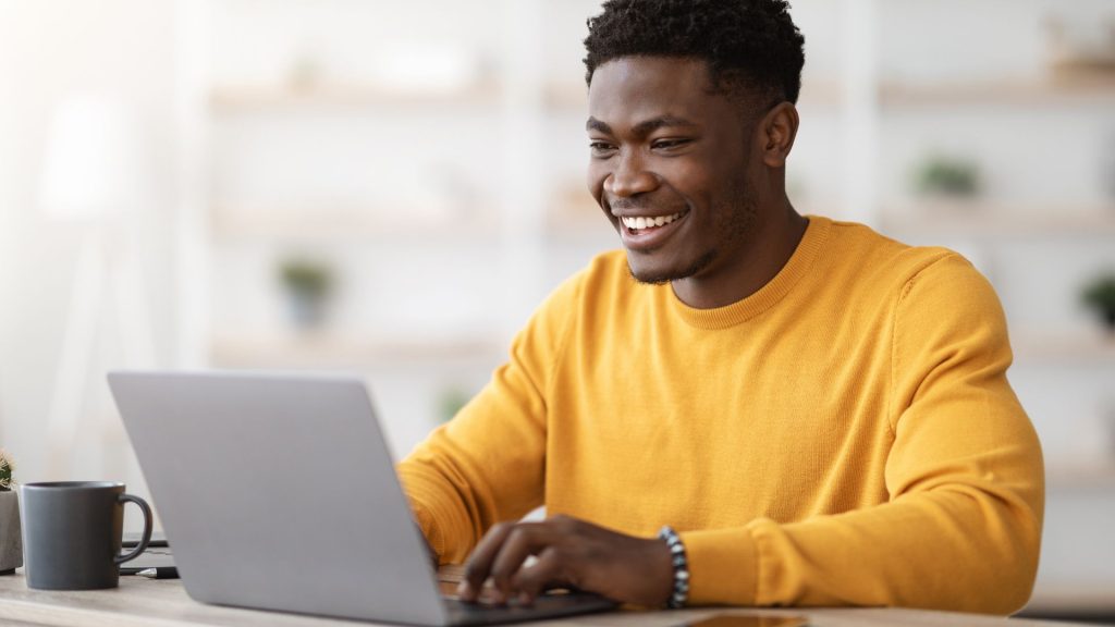 a man in a yellow shirt using a laptop